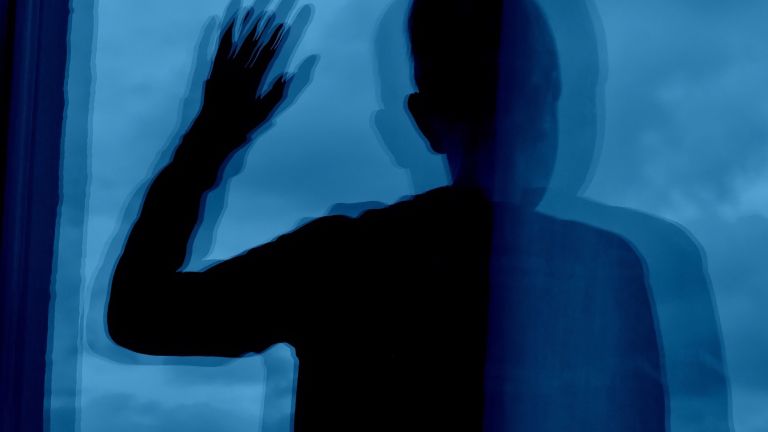 Eine Person spiegelt sich mehrfach in einer Fensterscheibe. Die bizarre Überlagerung der Spiegelungen soll das veränderte Handlungsempfinden von Patientinnen und Patienten mit Schizophrenie darstellen.